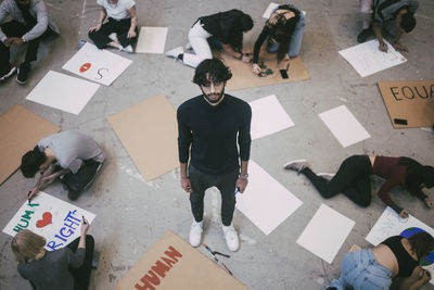 Portrait of man standing while male and female preparing signboards in building