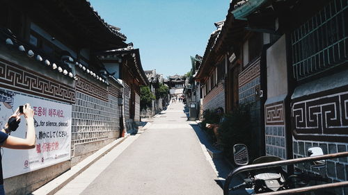 People on street amidst buildings against clear sky