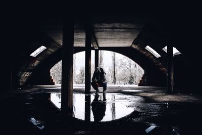 Full length of man crouching on puddle in abandoned building