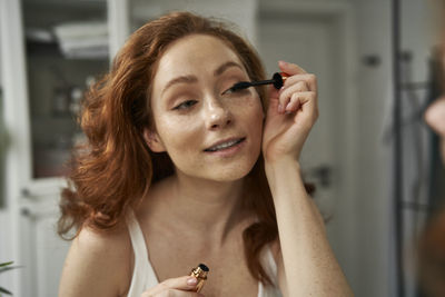 Young woman applying makeup at home