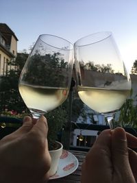 Close-up of hand holding wine glass against sky