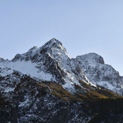 Low angle view of snowcapped mountains against clear sky