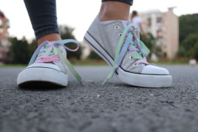 Low section of woman wearing canvas shoes while standing on street