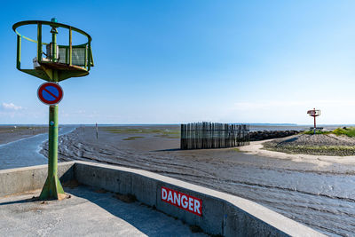 Road sign on beach against clear blue sky