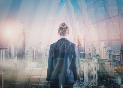 Rear view of woman standing against buildings in city