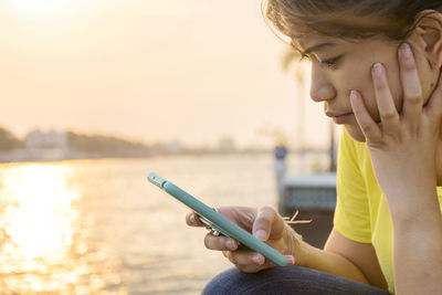 Midsection of woman holding mobile phone against sky