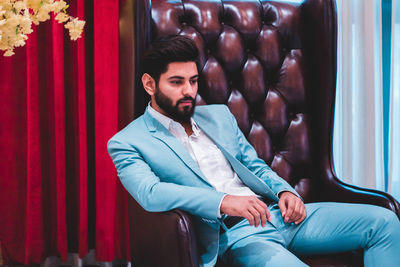 Young man looking away while sitting on seat