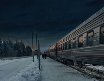 Train on snow covered railroad tracks against sky during winter