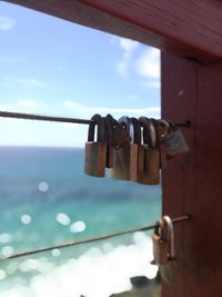 Close-up of padlocks hanging on metal against sky