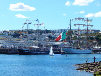 Boats moored at harbor against sky