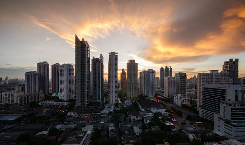 Modern buildings in city against sky during sunset