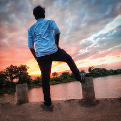 Rear view of man standing against sky during sunset