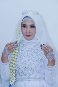 Portrait of young woman standing against white background