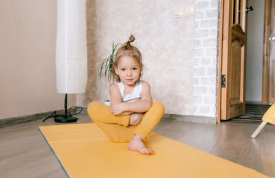 Portrait of smiling girl sitting on wooden floor at home