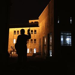 Silhouette man standing in illuminated city at night