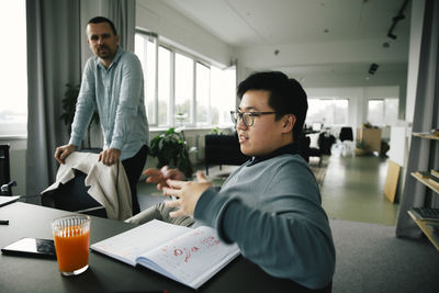 Young businessman discussing while sitting at desk in meeting