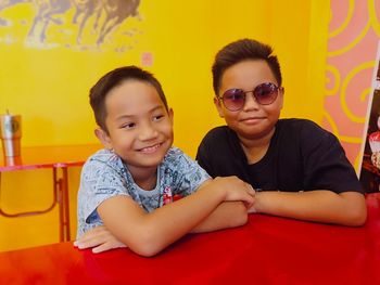 Portrait of smiling friends sitting on table