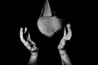 Cropped hands of man catching exploding water bomb against black background