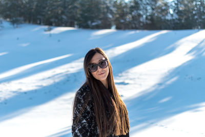 Portrait of young woman on snow covered landscape during winter