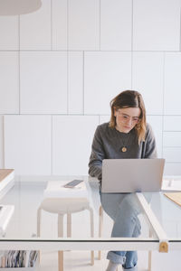 Young female entrepreneur using laptop at desk in design studio