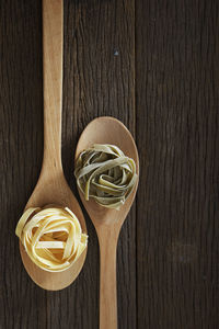 Close-up of tagliatelle pasta in wooden spoons on table