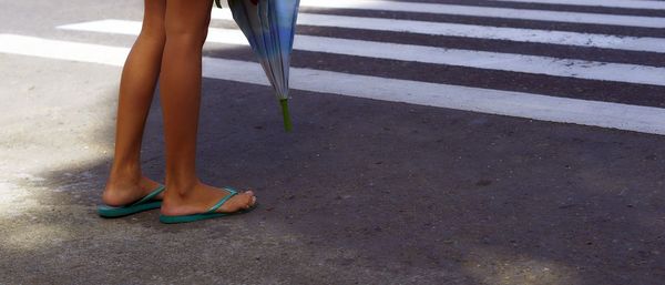 Low section of woman standing on zebra crossing