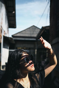Portrait of woman holding sunglasses against built structure