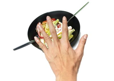 Close-up of hand holding ice cream against white background