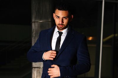 Portrait of young man standing against wall