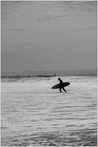 Silhouette surfer walking at beach