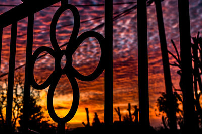 Close-up of silhouette metal grate against sky during sunset