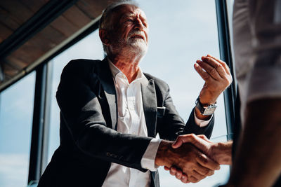 Low angle view of business person shaking hand while having discussion in office