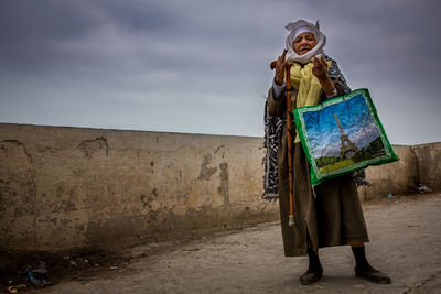 Woman standing with umbrella against sky