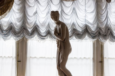 Side view of woman standing against window