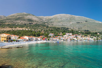 Scenic view of sea and mountains against clear blue sky