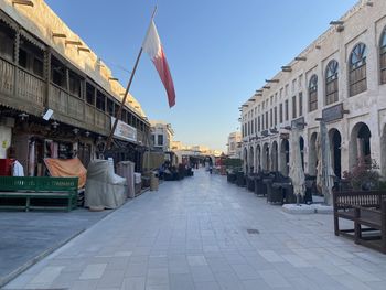 People on street amidst buildings against sky in city