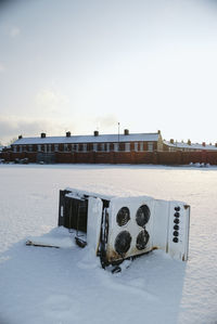 Built structure on snow covered field by building against sky