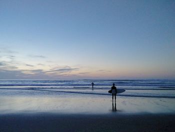 Silhouette man standing on beach against sky during sunset