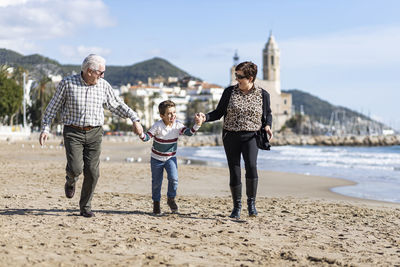 Happy grandparents with grandson running at beach