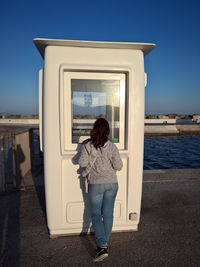 Rear view of woman standing by sea against sky