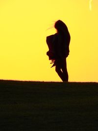 Silhouette woman on field against clear sky during sunset