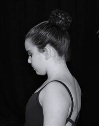 Side view of ballet dancer against black background