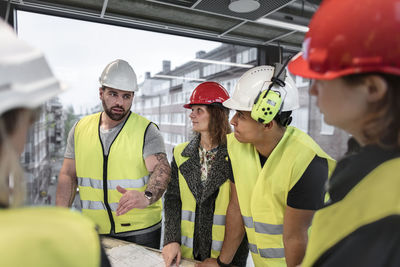 Workers reviewing blueprint at construction site