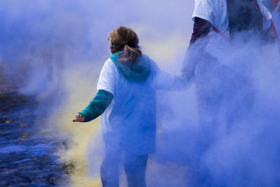 Rear view of mother and daughter standing amidst powder paint during holi