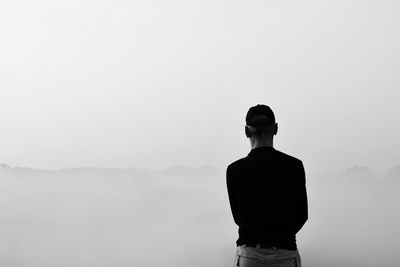 Rear view of man standing against clear sky