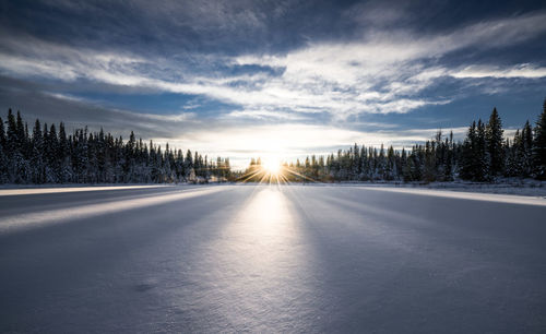 Snow covered landscape against sky during sunset