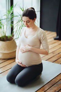 Side view of young woman exercising at home