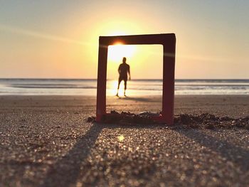 Silhouette man standing on beach against clear sky during sunset