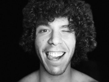 Portrait of smiling young man against black background