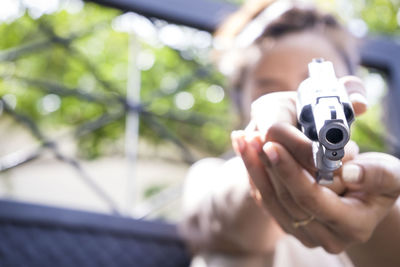 Woman holding handgun by gate